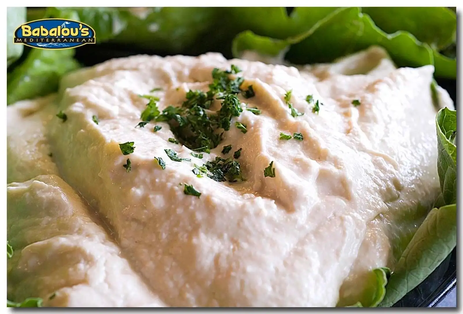 Creamy hummus garnished with chopped herbs